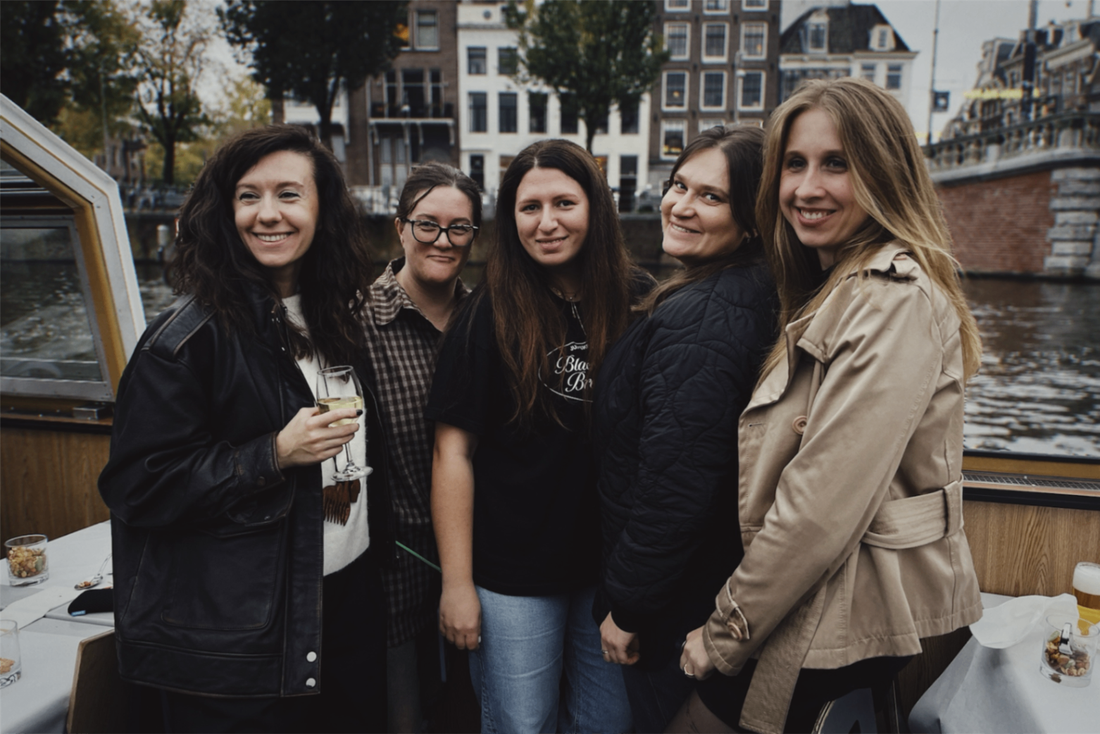 Five delegation participants smiling together on a canal boat during an evening city cruise
